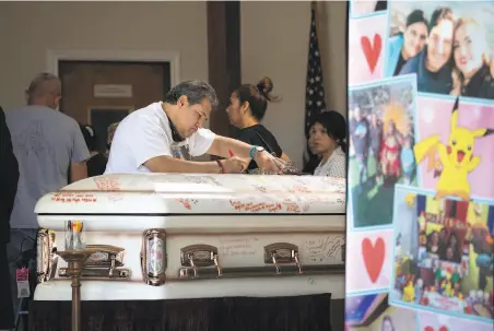  ?? Jim Gensheimer / Special to The Chronicle ?? A funeral participan­t writes a message on the casket as friends and family gather to honor the life of 13yearold Keyla Salazar.