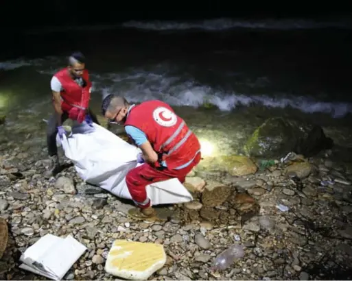  ??  ?? Rode Kruis dragen het lijk van een verdronken migrant weg in Tajoura, zo’n 14 km ten oosten van Tripoli. © epaefe