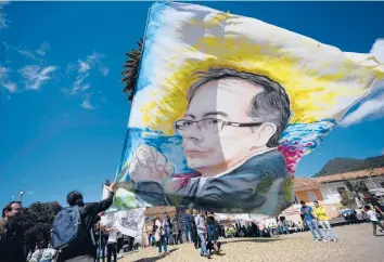  ?? FERNANDO VERGARA/AP ?? A supporter of Colombian presidenti­al candidate Gustavo Petro holds a flag emblazoned with Petro’s image before a closing campaign rally Monday in Zipaquira, Colombia. Voters are scheduled to go to the polls on Sunday.