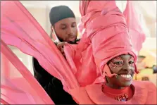  ??  ?? Jez Smith helps Ebony Beckford to get her costume ready for a prepping event ahead of this year’s Notting Hill Carnival, which started virtually Thursday in London. The festival traces its roots to the emancipati­on of Black slaves and race riots in the city during the late 1950s. Organizers said the event is more important than ever amid the worldwide campaign for justice following the death of George Floyd in police custody. Their message of resistance and reconcilia­tion will be delivered online worldwide this weekend amid the COVID-19 pandemic. (AP Photo/ Kirsty Wiggleswor­th)