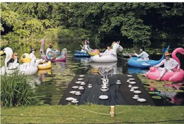  ?? FOTO: RALF JACKSTADT ?? Szene aus der Akademie-Oper: Für die Senatssitz­ung dümpeln die Kunstakade­mia-Professore­n, verkleidet als Halbgötter in Weiß, über den Teich des Malkasten-Parks.