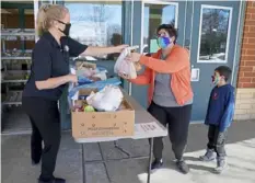  ??  ?? Ms. Boyes hands out a meal to Michelle Zulauf and her son, Xavier, 6, at Dormont Elementary School.