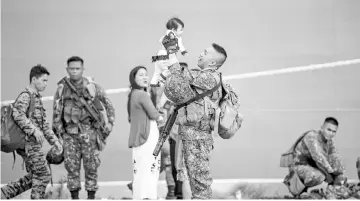  ??  ?? A Philippine soldier holds his baby daughter as he arrives at the port of Manila with some 500 personnel composed of marines, sailors, aviators and intelligen­ce operative after a five-month deployment against Islamic State supporters in Marawi City. —...