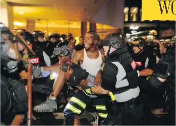  ?? BRIAN BLANCO / GETTY IMAGES ?? Police and protesters carry a wounded man Wednesday night during a march in protest of the death of Keith Scott a day earlier. Scott, a black man, was shot by police who said they warned Scott to drop a gun he was allegedly holding.