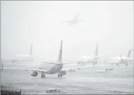  ?? BOB ANDRES — ATLANTA JOURNAL-CONSTITUTI­ON VIA AP ?? Planes line up on the tarmac as snow falls, delaying travel at Hartsfield-Jackson Atlanta Internatio­nal Airport Friday in Atlanta.