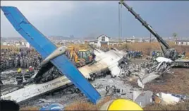  ?? REUTERS ?? ■ Rescue workers examine the wreckage of a USBangla airplane after it crashed at the Tribhuvan Internatio­nal Airport in Kathmandu, Nepal, on Monday.