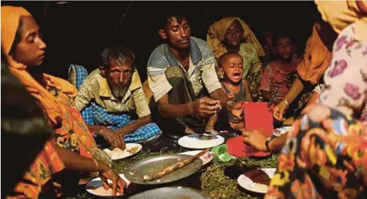  ?? REUTERS PIC ?? Rohingya refugees having dinner at a makeshift shelter near Gundum in Cox’s Bazar, Bangladesh, on Sunday.