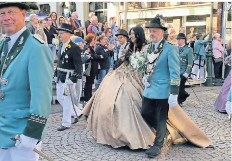  ?? FOTO: BÄRBEL BROER ?? Das Kleid von Schützenkö­nigin Andrea Mews ist ein besonderer Eyecatcher. Neben Petticoat mit Schleppe führt ihr Mann, Schützenkö­nig Volker Mews, sie durch den Ort in Richtung Festzelt.