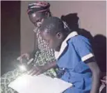  ?? ?? Brandina helping her daughter with homework after school at her homestead in Simatelele village on November 2, 2021. When the rig was working she could pay school fees and buy uniforms with less difficulti­es