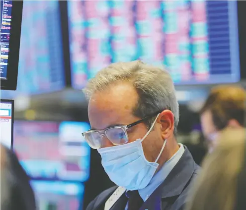  ?? LUCAS JACKSON / REUTERS ?? A trader wears a mask as he works on the floor of the New York Stock Exchange on Friday.