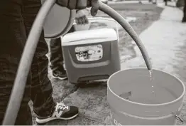  ?? Brett Coomer / Staff photograph­er ?? People fill containers of various sizes from a spigot at Haden Park on Thursday as Houston and surroundin­g communitie­s were under a boil water notice.