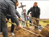  ?? Carolyn Cole Los Angeles Times ?? YRYNA CHEBOTOK holds the cross that will mark her grandfathe­r Volodymyr Rubaylo’s grave in Bucha.