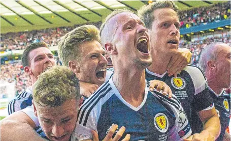  ?? Picture: SNS. ?? Two-goal hero Leigh Griffiths is swamped by team-mates after equalising for Scotland.