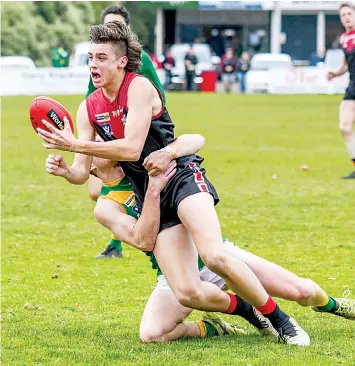  ?? Photograph­s by CRAIG JOHNSON. ?? Liam Serong manages to get his handpass away despite a strong tackle from his Leongatha opponent.