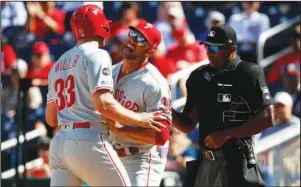  ?? The Associated Press ?? BYE-BYE, BRAD: Philadelph­ia Phillies manager Gabe Kapler, center, holds back Brad Miller as Miller argues with umpire Alan Porter after striking out looking in the sixth inning of the first game of Tuesday’s doublehead­er against the Washington Nationals in Washington. Miller was ejected from the game after the at-bat.