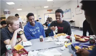  ??  ?? LEWISTON: Abdiaziz Shaleh, right, a Lewiston high school senior and co-captain of the soccer team, and Essa Gedi, center, both whose families emigrated from Somalia, sit with classmate Isiah Leach, left, during lunch in the school’s cafeteria.