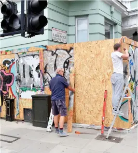  ??  ?? Barriers: Workmen putting up wooden hoardings around homes on Ladbroke Grove, which is part of the carnival’s parade route