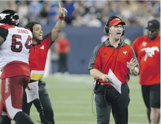  ?? KEVIN KING ?? Calgary Stampeders head coach Dave Dickenson applauds an intercepti­on return for a touchdown during action against the Blue Bombers in Winnipeg on Thursday.