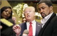  ?? THE ASSOCIATED PRESS ?? Republican presidenti­al candidate Donald Trump, center, talks with reporters following a meeting with a coalition of 100 African-American evangelica­l pastors and religious leaders in a meeting in New York on Nov. 15, 2015.