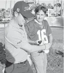  ?? Marco Garcia / Associated Press ?? Justin Thomas, left, helps golf partner Kevin Kiser, a Georgia graduate, put on an Alabama football jersey to settle a bet during the first round of the Sony Open tournament.