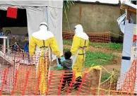  ?? AP ?? Health workers walk with a boy suspected of having the Ebola virus at an Ebola treatment centre in Beni, Eastern Congo.