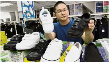  ?? Growing concern: ?? Quak showing the white and black school shoes at his shop in Bukit Mertajam.