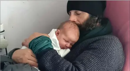  ?? ?? Ex-paratroope­r Christian Lewis, who has raised more than £340,000 by walking around the UK’S coastline, gives his newborn son Magnus a hug