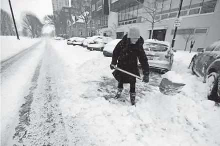  ?? PHOTOS BY MIKE DE SISTI/MILWAUKEE JOURNAL SENTINEL ?? Erin Flora of Milwaukee clears snow from her car Sunday near the corner of East Kilbourn Avenue and North Cass Street in Milwaukee. Parts of Milwaukee and Ozaukee counties were dumped on with around 10 inches of snow overnight as a snowstorm moved in, and then lake effect snow added to the accumulati­on.