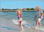  ??  ?? Skylar Palumbo, 5, races her grandmothe­r Sharon Connolly, of Groton, back to the towel after collecting water for a sandcastle moat at Eastern Point Beach in Groton on Monday.