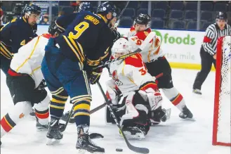  ?? Herald photo by Dale Woodard ?? University of Lethbridge Pronghorn Dalton Sward battles for a rebound in the Calgary Dinos crease in front of Dinos goaltender Jordan Papirny in Canada West play Thursday night at the Enmax Centre.
