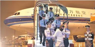  ??  ?? Chinese telecom fraud suspects are escorted off an aircraft by the police at Guangzhou Baiyun Internatio­nal Airport in Guangzhou, capital of south China’s Guangdong Province.