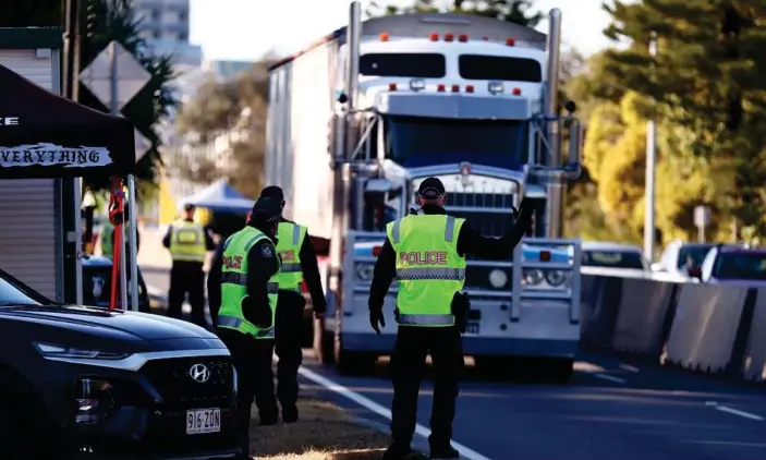  ?? Photograph: Chris Hyde/Getty Images ?? Queensland police stop trucks at the border in Coolangatt­a on Wednesday. The Queensland government has further tightened restrictio­ns for people travelling into the state from NSW.