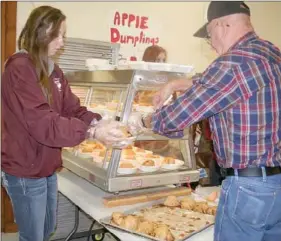  ?? PAT HARRIS ENTERPRISE-LEADER ?? Tara Myers, a Lincoln High School student, and Larry Hacker, a Kiwanis club member, helped dish up and serve apple dumplings at the Lincoln Community Center during the Arkansas Apple Festival held on the square in Lincoln over the weekend.