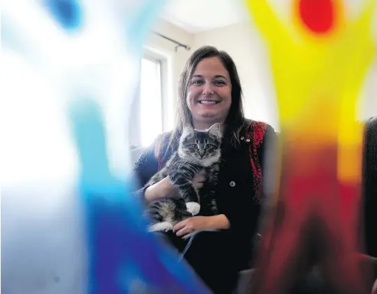  ?? RONALD ZAJAC ?? Jenn Coward and her kitten, Ivy, are seen through the Inspiratio­n Award trophy she won from The Royal Ottawa, in Brockville, Ont.
