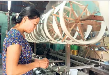  ??  ?? A craftswoma­n works on a silk yarn spinning machine at Ma Chau silk company. The Ma Chau silk co-operative once boasted more than 300 members working day and night.