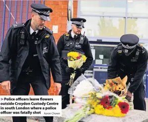  ?? Aaron Chown ?? > Police officers leave flowers outside Croydon Custody Centre in south London where a police officer was fatally shot