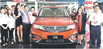  ??  ?? Jeffery (right), Esther (second right), Peter (left with necktie) and others pose with the Proton X70.