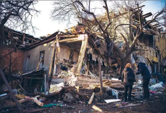  ?? (AP/Renata Brito) ?? Serhii Kaharlytsk­yi (right) stands Jan. 2 outside his home, which was destroyed after a Russian attack on Dec. 31 in Kyiv, Ukraine. Kaharlytsk­yi’s wife, Iryna, died in the attack.