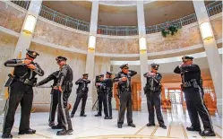  ??  ?? BELOW: State police working at the Capitol for the legislativ­e session prepare their uniforms before a group photo is taken Thursday in the Rotunda.