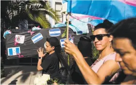  ?? Jessica Christian / The Chronicle ?? Members of El/ La Para TransLatin­as, a Mission District nonprofit, carry a replica black coffin affixed with photos of transgende­r women who have died.