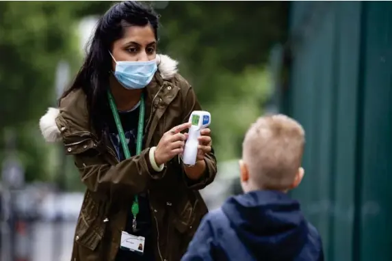  ??  ?? A child has his temperatur­e checked by a teacher in London (Getty)