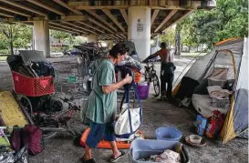  ?? Yi-Chin Lee / Houston Chronicle ?? While Jahki Ptah brings their belongings, his girlfriend Michelle Friedenbac­k organizes after moving back under the overpass that was cleaned Thursday.