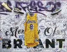  ?? DAMIAN DOVARGANES - THE ASSOCIATED PRESS ?? Sneakers and a Los Angeles Lakers uniform with the numbers worn by NBA star Kobe Bryant are left at a memorial for Bryant while fans gather to pay their respects near Staples Center in Los Angeles on Feb. 2, 2020. Bryant, who became one of the greatest basketball players of his generation during a 20-year career with the Lakers, died in a helicopter crash on Sunday, Jan. 26.
