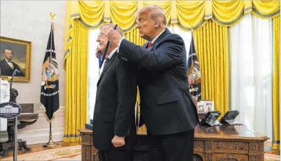  ?? Evan Vucci The Associated Press ?? President Donald Trump presents the Presidenti­al Medal of Freedom to former football coach Lou Holtz in the Oval Office.