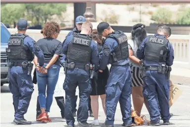  ??  ?? Tempe police put the cuffs on three women as they were arrested Thursday in a protest on the Mill Avenue Bridge. Police said they were arrested after refusing warnings to move off the roadway.