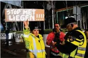  ?? PETER DEJONG / AP ?? A police officer checks the ID of a protester holding a sign that reads “Stop Lying” in The Hague, Netherland­s, on Friday.