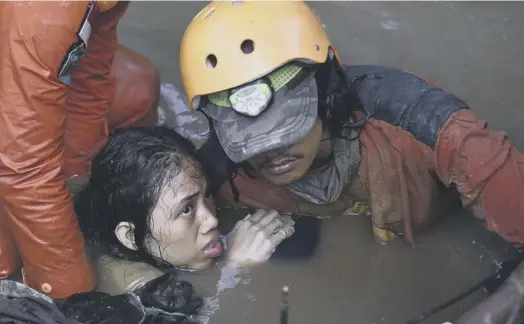  ??  ?? 2 Rescuers help a traumatise­d survivor from a damaged house in the city of Palu in central Sulawesi yesterday after the earthquake and tsunami struck in Indonesia on Friday