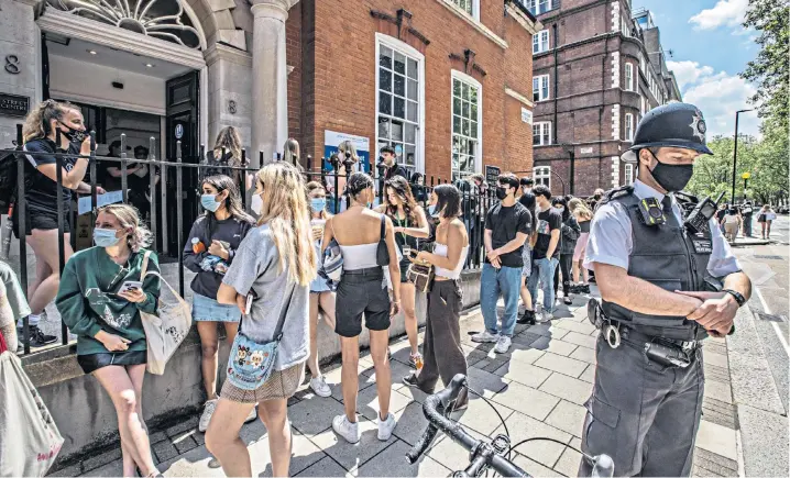  ??  ?? A Metropolit­an Police officer attends the scene as UCL students queue outside the Hunter Street Clinic near King’s Cross station yesterday