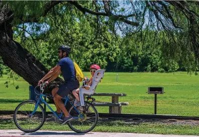  ?? Carlos Javier Sanchez / Contributo­r file photo ?? A man takes a child on a bike ride at Brackenrid­ge Park in April. In the previous month, bicycle sales nationwide surged 50 percent, according to the NPD Group, a market research company.