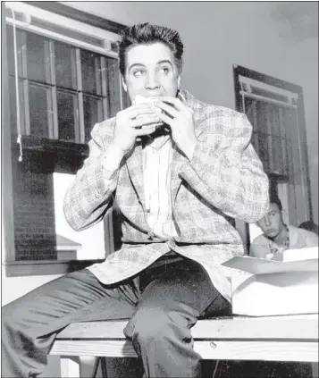  ?? BARNEY SELLERS / THE COMMERCIAL APPEAL FILES ?? The Army provided a box lunch for Elvis Presley and other inductees the day they reported for duty March 24, 1958, at Fort Hood, Texas. Elvis ate parts of ham and beef sandwiches, drank a glass of milk and ate a piece of apple pie and an apple. The King’s diet has been a subject of comedy and lore, but it was fairly typical for his time.